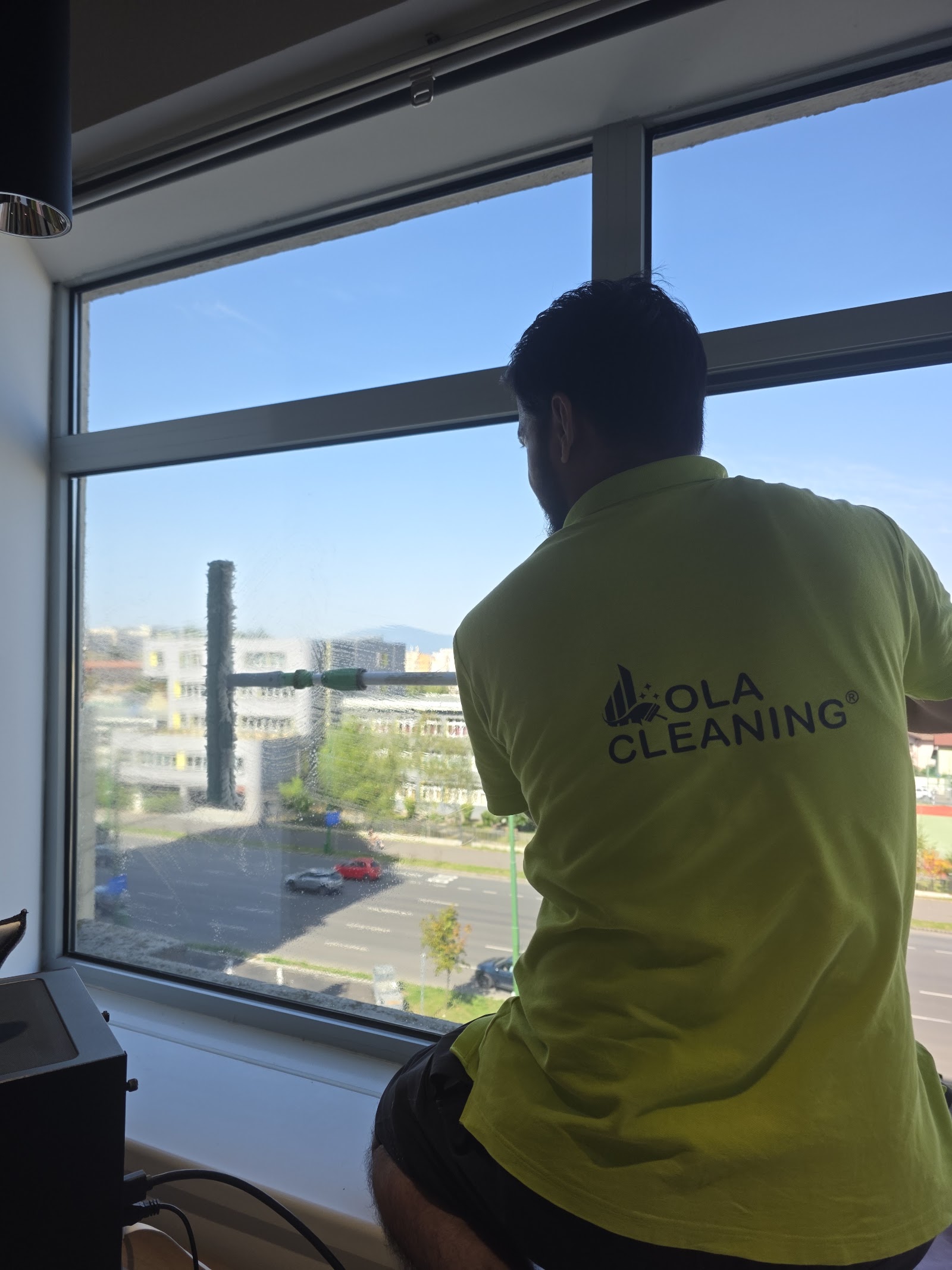 Angajat Ola Cleaning spală geamurile unui birou din Brașov
